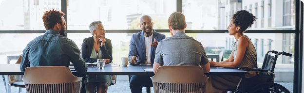 A collective of people that are sitting in a conference room desk